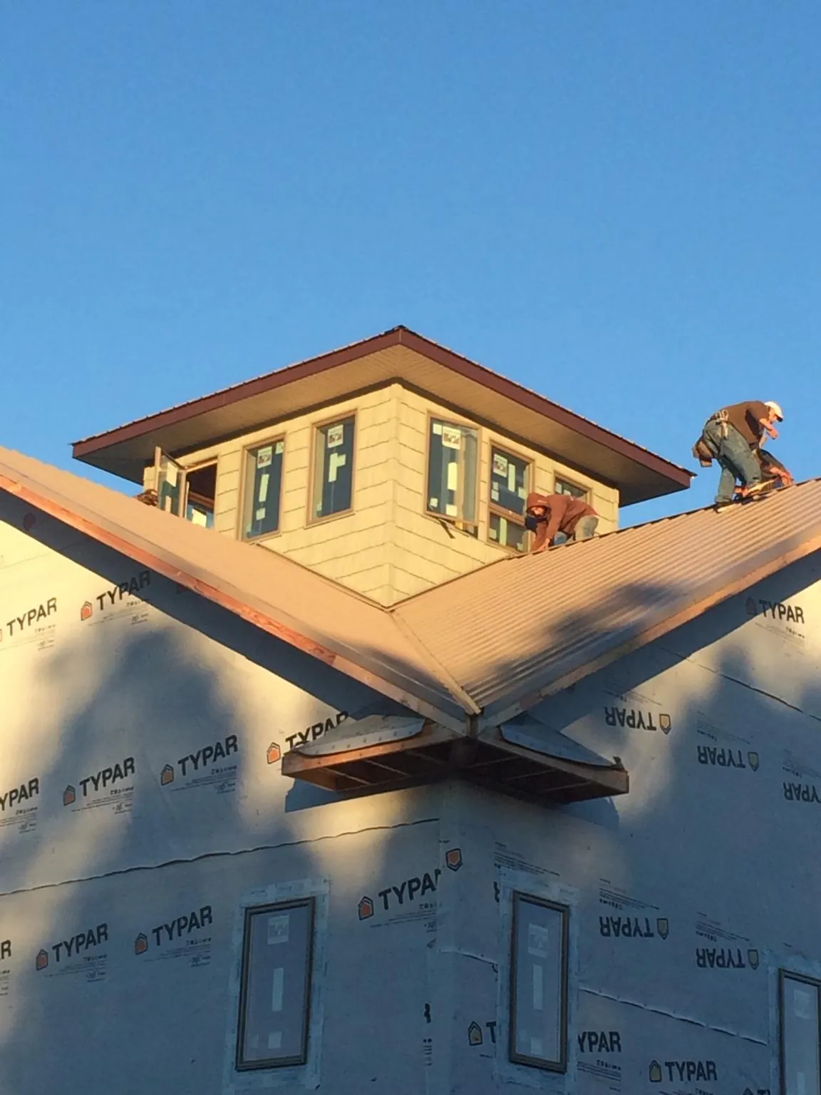 Roofers working around a rooftop cupola on a new metal roof at sunset — Roof Waterproofing in Millington by Roofing Brothers